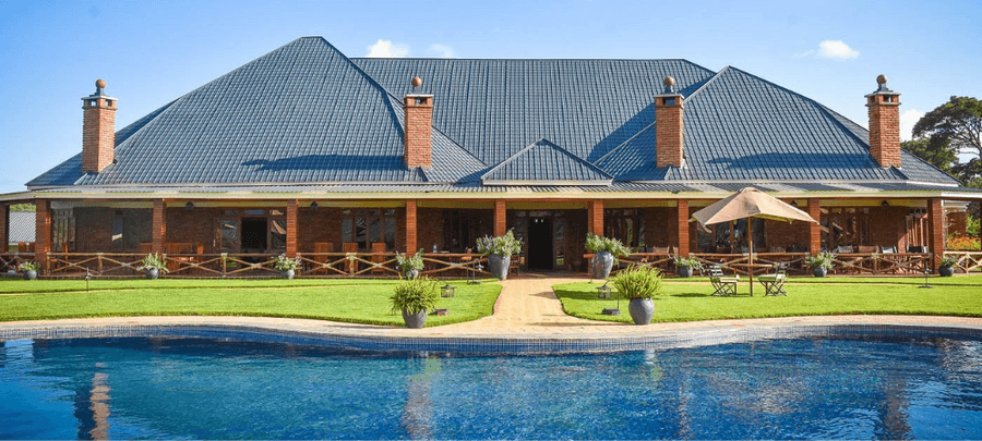 Marera Valley Lodge exterior with a swimming pool, lush gardens, and spacious terrace set against a scenic Karatu landscape