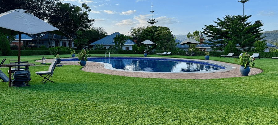 Swimming pool at Marera Valley Lodge surrounded by lush gardens, sun loungers, and scenic views of the Karatu highlands