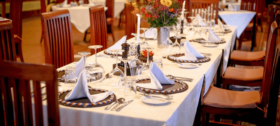 Elegant dining setup at Marera Valley Lodge with neatly arranged table settings, glassware, and floral centerpiece in a warm, inviting restaurant