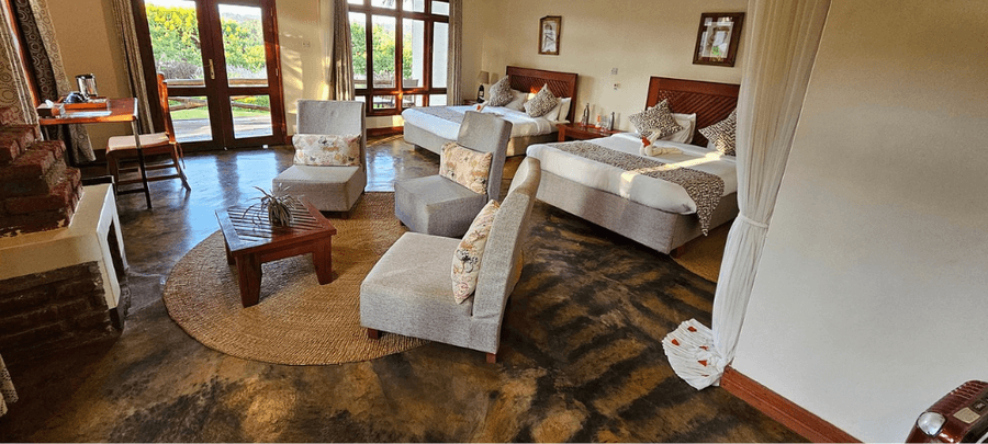 Spacious room at Marera Valley Lodge with twin beds, cozy seating area, and large windows opening to garden views