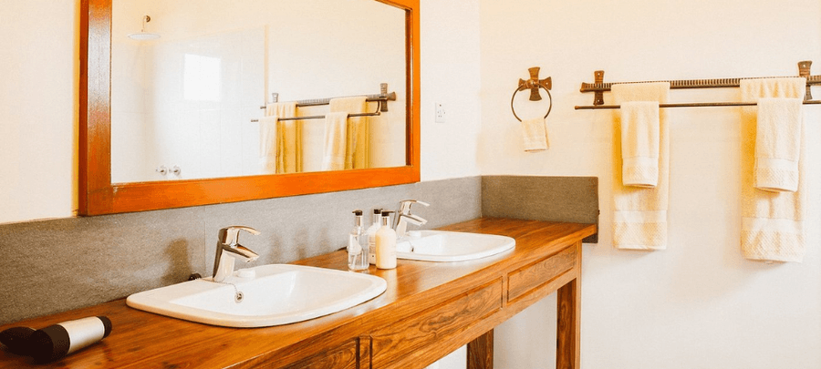 Modern bathroom at Marera Valley Lodge with double sinks, wooden vanity, large mirror, and neatly arranged towels.