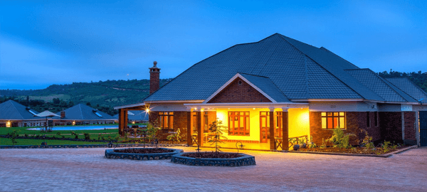 Marera Valley Lodge at dusk, featuring a warmly lit exterior, landscaped gardens, and scenic highland views in Karatu, Tanzania