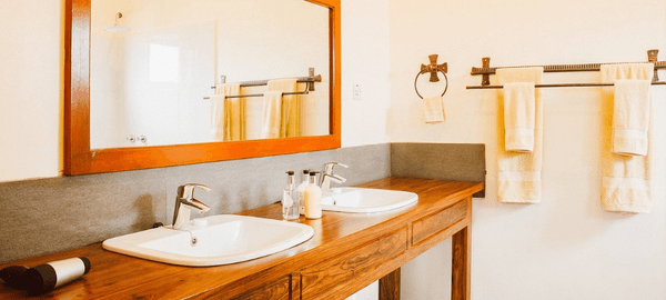 Modern bathroom at Marera Valley Lodge with double sinks, wooden vanity, large mirror, and neatly arranged towels.